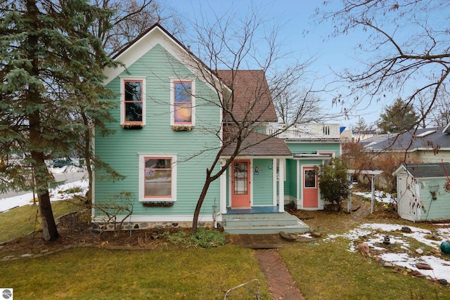 victorian-style house featuring a storage shed, a front lawn, and an outdoor structure
