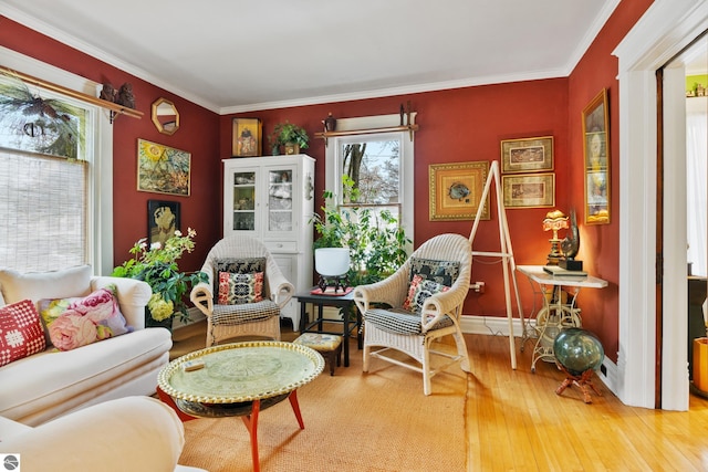 living area featuring baseboards, crown molding, and hardwood / wood-style flooring