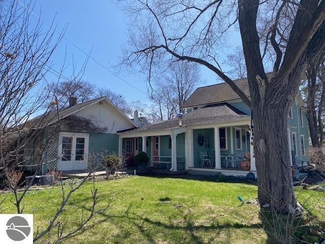 back of property featuring a lawn and covered porch