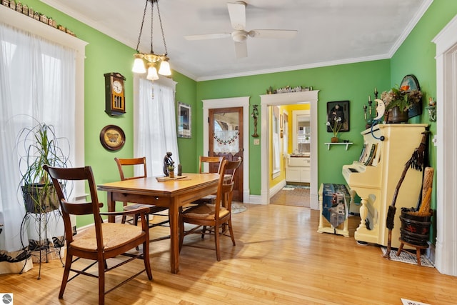 dining room featuring ornamental molding, baseboards, a ceiling fan, and light wood finished floors