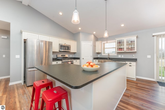 kitchen featuring a center island, lofted ceiling, a kitchen breakfast bar, appliances with stainless steel finishes, and white cabinetry