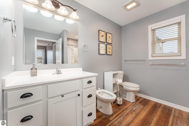 bathroom with vanity, toilet, a bidet, and hardwood / wood-style flooring