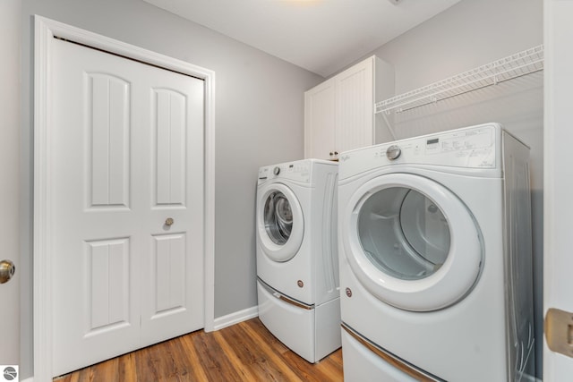 laundry area with washer and clothes dryer, dark hardwood / wood-style flooring, and cabinets