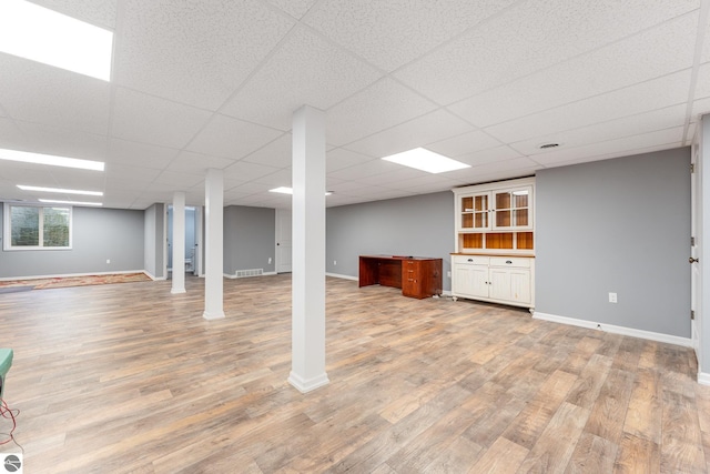 basement with a paneled ceiling and hardwood / wood-style floors