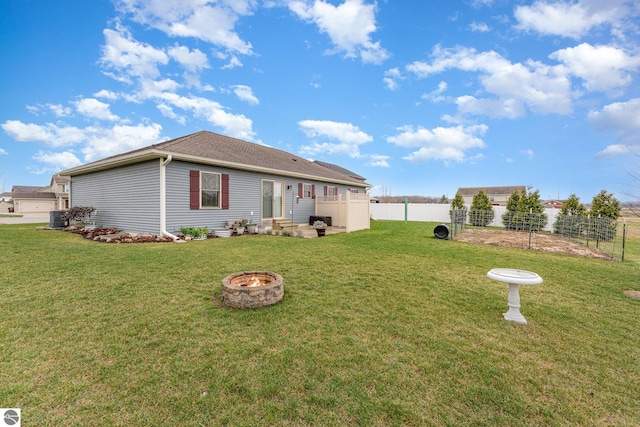 back of property featuring central air condition unit, a yard, and a fire pit