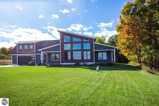 rear view of house featuring a garage and a lawn