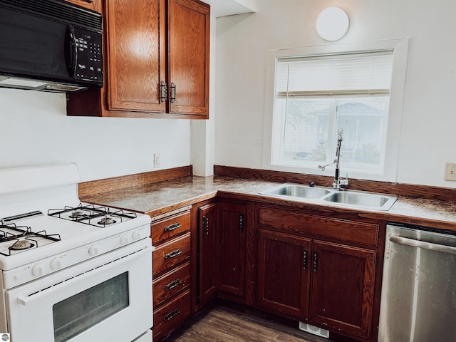 kitchen featuring stainless steel dishwasher, sink, white range with gas cooktop, and dark wood-type flooring