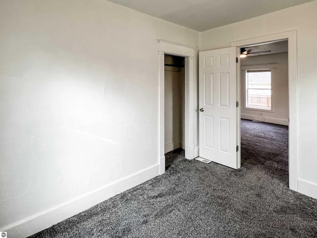 unfurnished bedroom with dark carpet and a closet