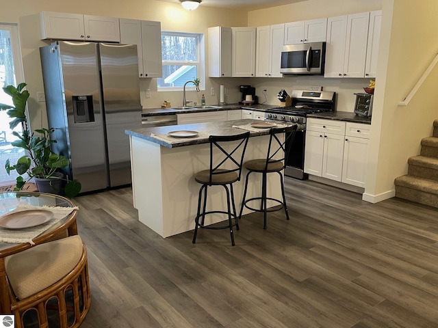 kitchen featuring white cabinets, appliances with stainless steel finishes, dark wood-type flooring, and sink