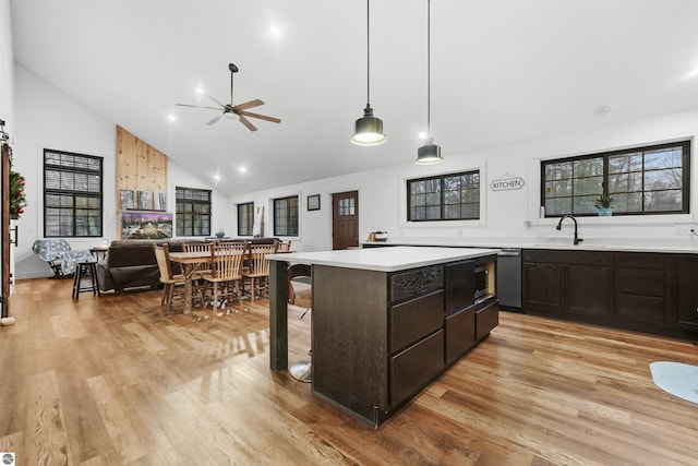 kitchen featuring high vaulted ceiling, sink, ceiling fan, light wood-type flooring, and decorative light fixtures