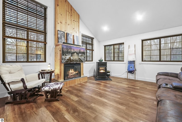 sitting room featuring a fireplace, a wood stove, hardwood / wood-style flooring, and high vaulted ceiling