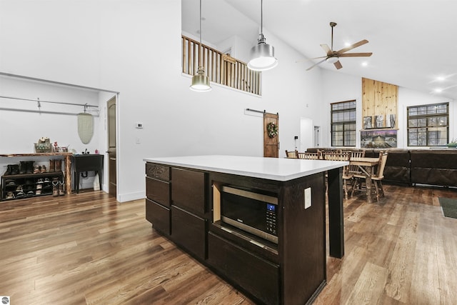 kitchen with a barn door, decorative light fixtures, high vaulted ceiling, hardwood / wood-style flooring, and a center island