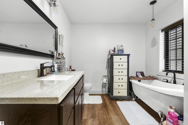 bathroom featuring vanity, hardwood / wood-style flooring, toilet, and a bathtub