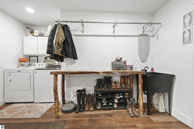 laundry room with washing machine and dryer, hardwood / wood-style floors, and cabinets