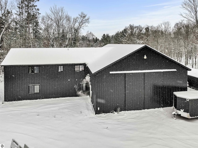 snow covered back of property with central AC unit and an outdoor structure