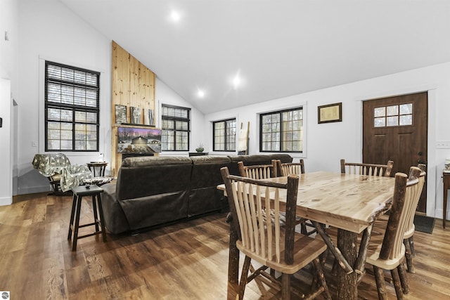 dining area with dark hardwood / wood-style flooring, high vaulted ceiling, and a healthy amount of sunlight