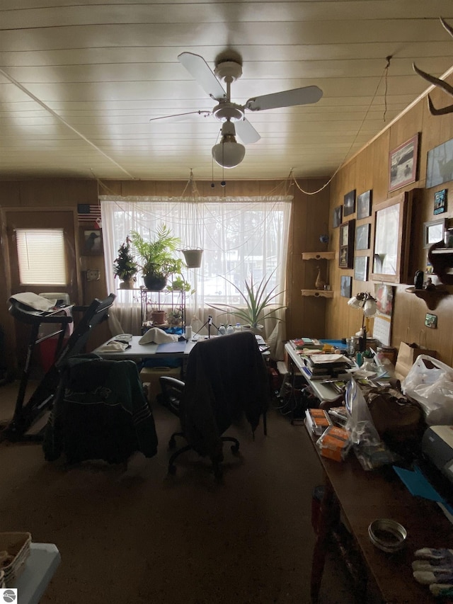 dining room with ceiling fan and wood walls