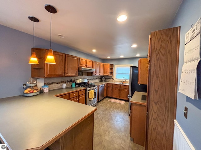 kitchen featuring stainless steel appliances, decorative light fixtures, kitchen peninsula, and sink