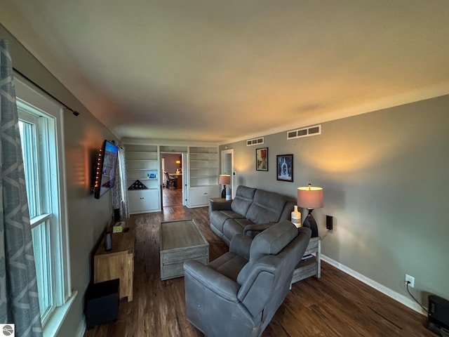 living room with dark hardwood / wood-style flooring and built in shelves