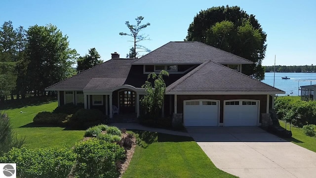 view of front of home with a water view, a front yard, and a garage