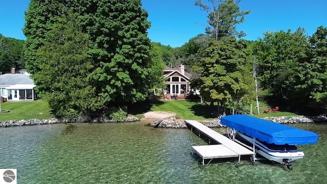 view of dock with a yard and a water view