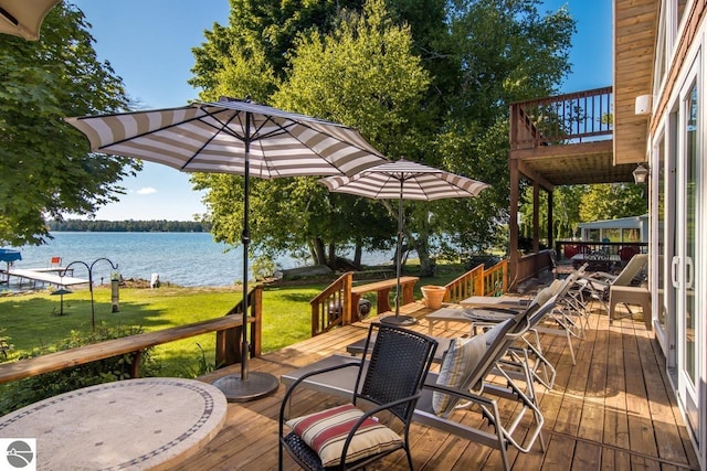 wooden terrace with a water view and a yard