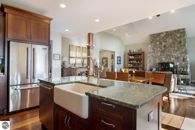 kitchen featuring a fireplace, a kitchen island with sink, sink, and stainless steel appliances