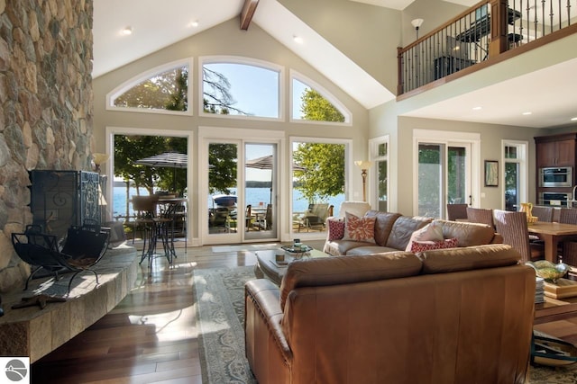 living room featuring plenty of natural light, a water view, wood-type flooring, and high vaulted ceiling