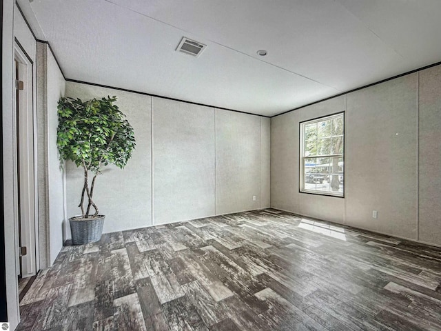 unfurnished room featuring ornamental molding and dark wood-type flooring