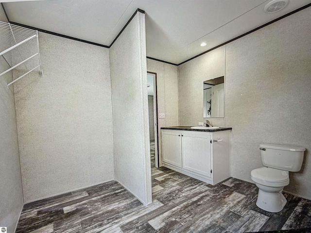 bathroom with vanity, toilet, ornamental molding, and hardwood / wood-style floors