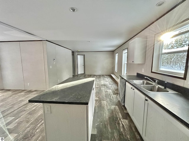 kitchen with white cabinets, a center island, dark hardwood / wood-style flooring, sink, and stainless steel dishwasher