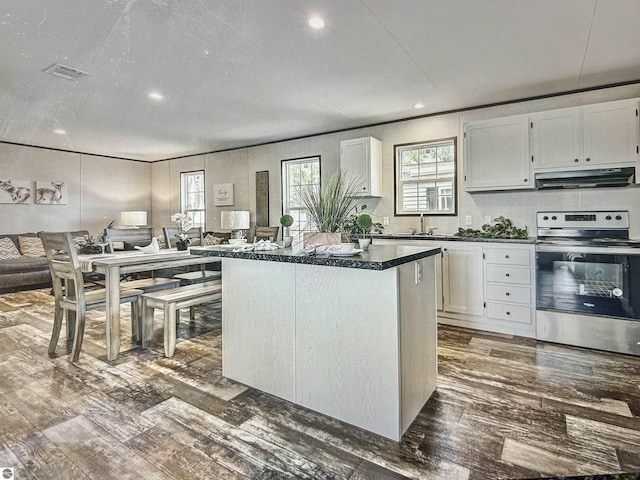 kitchen with a kitchen island, white cabinets, dark wood-type flooring, and electric stove