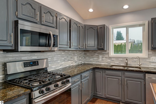 kitchen featuring sink, stainless steel appliances, and dark stone counters