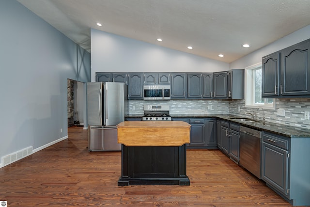 kitchen with sink, dark hardwood / wood-style flooring, a kitchen island, and appliances with stainless steel finishes