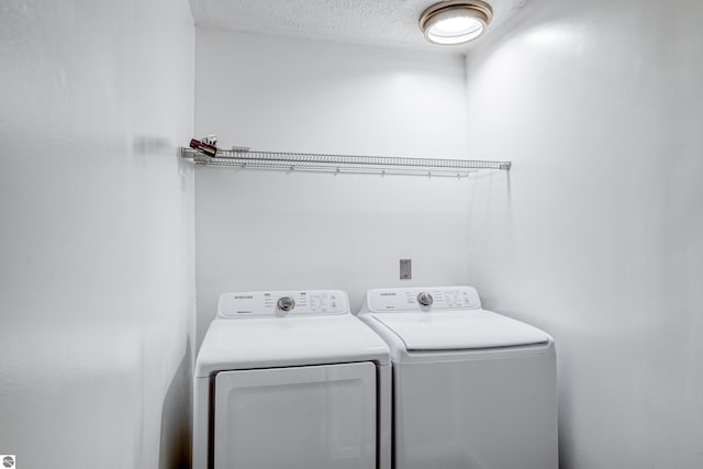 washroom with washing machine and clothes dryer and a textured ceiling