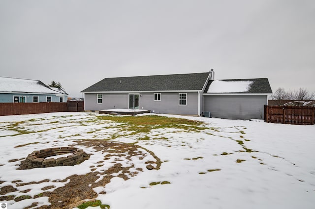 snow covered rear of property featuring a fire pit