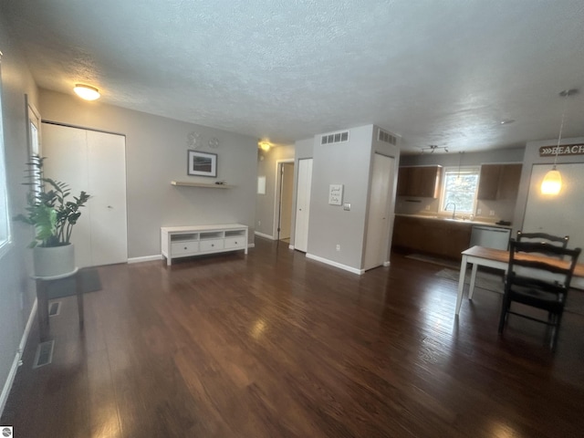 living room with sink, dark wood-type flooring, and a textured ceiling