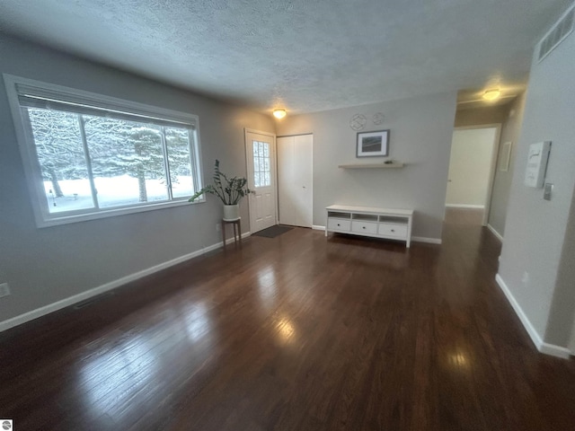 unfurnished living room featuring a textured ceiling and dark hardwood / wood-style flooring