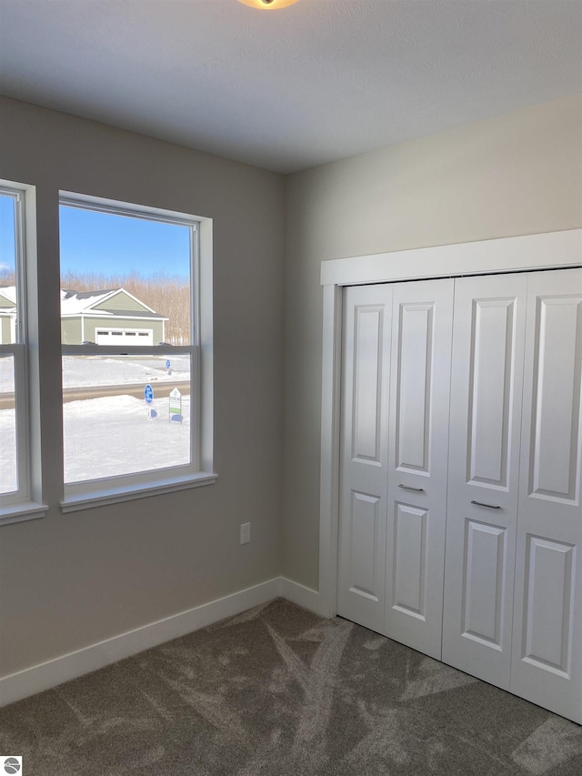 unfurnished bedroom with dark carpet and a closet