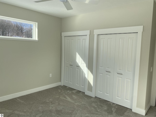 unfurnished bedroom featuring carpet floors, ceiling fan, and multiple closets