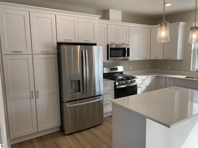 kitchen with white cabinets, hanging light fixtures, and appliances with stainless steel finishes