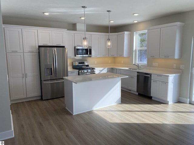 kitchen featuring pendant lighting, a center island, stainless steel appliances, and white cabinetry