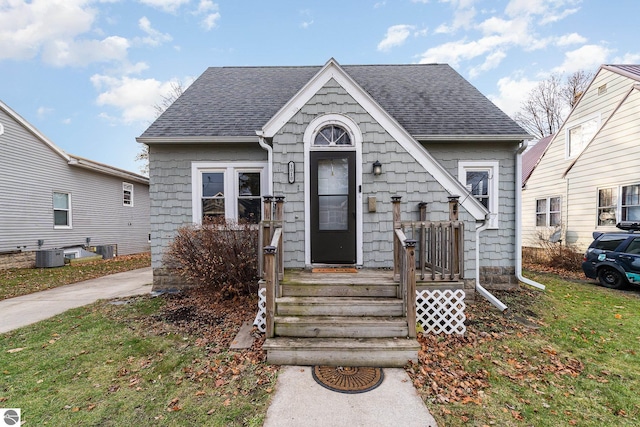 bungalow-style house featuring a front lawn and central AC unit