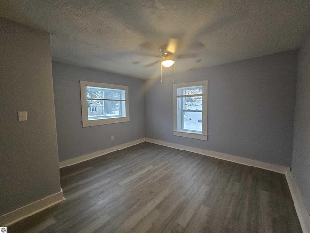 empty room featuring a textured ceiling, dark hardwood / wood-style flooring, and ceiling fan