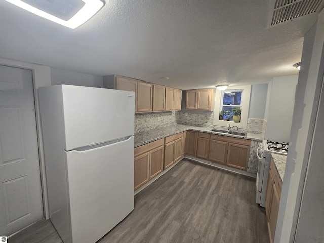 kitchen with white appliances, sink, dark hardwood / wood-style floors, light stone countertops, and tasteful backsplash