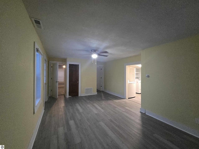 spare room with a textured ceiling, ceiling fan, dark wood-type flooring, and washer / clothes dryer