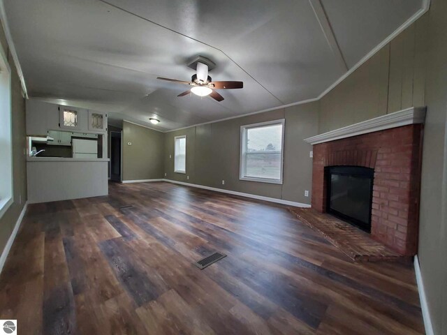 unfurnished living room with a fireplace, vaulted ceiling, and dark wood-type flooring