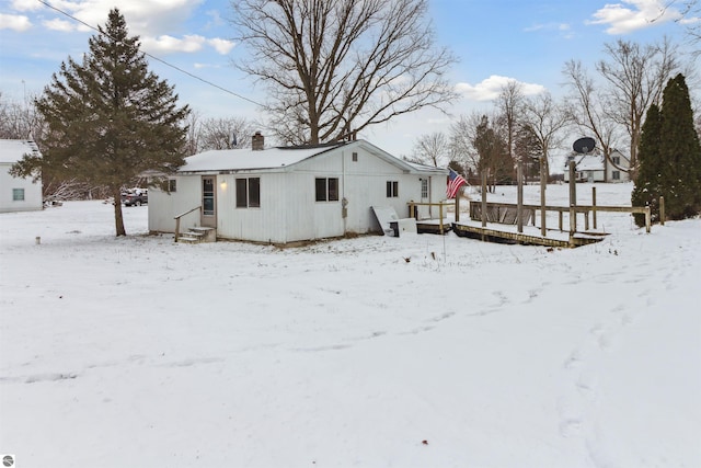 snow covered rear of property with a deck