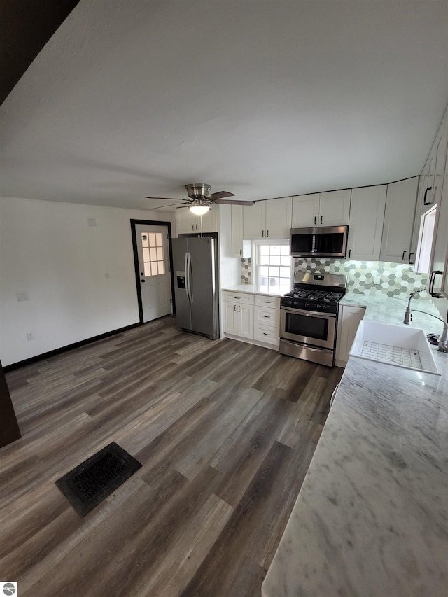 kitchen featuring decorative backsplash, appliances with stainless steel finishes, sink, white cabinets, and dark hardwood / wood-style floors