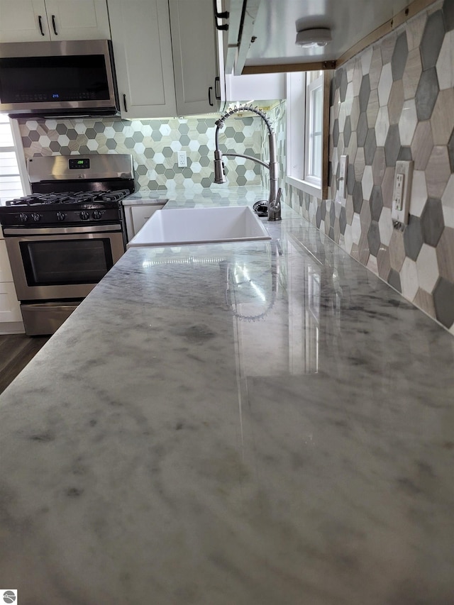 kitchen featuring white cabinets, appliances with stainless steel finishes, backsplash, and sink